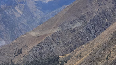 Terraced agricultural fields in the Inca Valley of Peru surrounded by dramatic mountain peaks.
