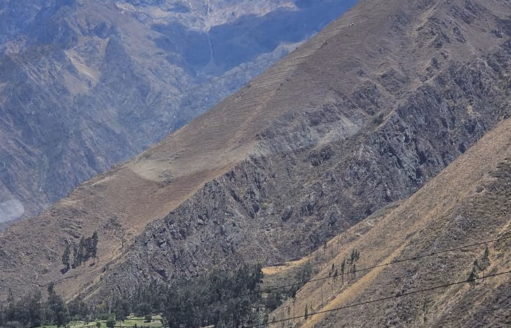 Terraced agricultural fields in the Inca Valley of Peru surrounded by dramatic mountain peaks.