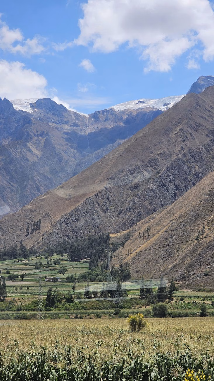 Terraced agricultural fields in the Inca Valley of Peru surrounded by dramatic mountain peaks.